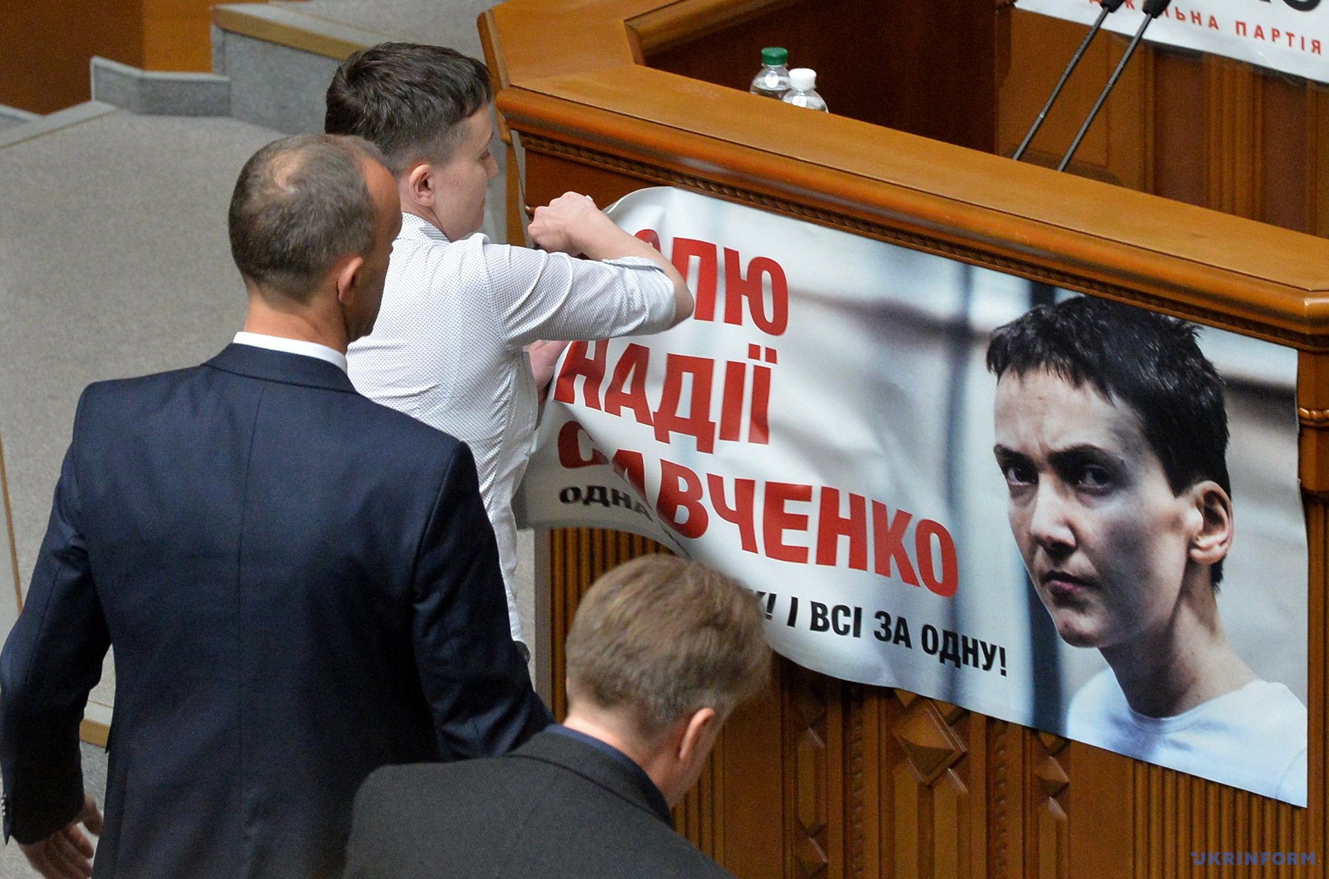 Надежда Савченко снимает плакат с надписью 