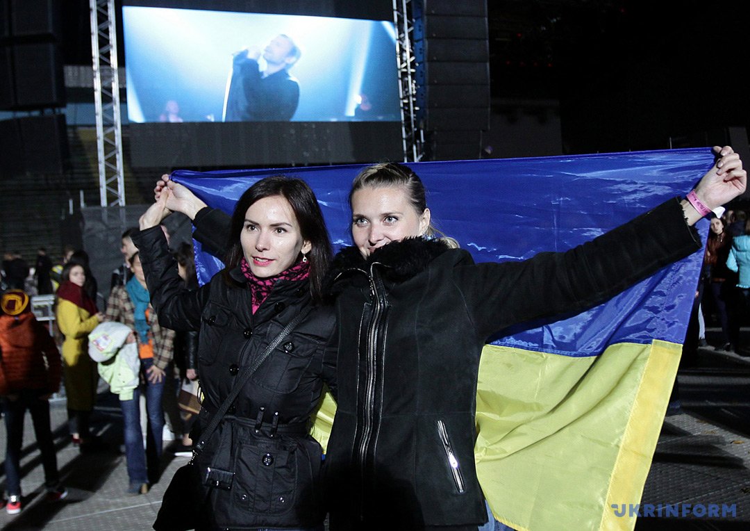 Девушки держат в руках государственный флаг Украины во время концерта группы Девушки держат в руках государственный флаг Украины во время концерта группы
