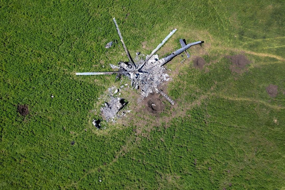 Reste eines russischen Hubschraubers liegen auf einem Feld mit Granatkratern in Biskwitne östlich von Charkiw. Foto: John Moore, instagram.com/jbmoorephoto
