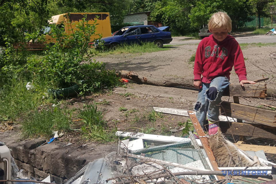 Хлопчик грається з котом у дворі зруйнованого Маріуполя / Фото: Укрінформ