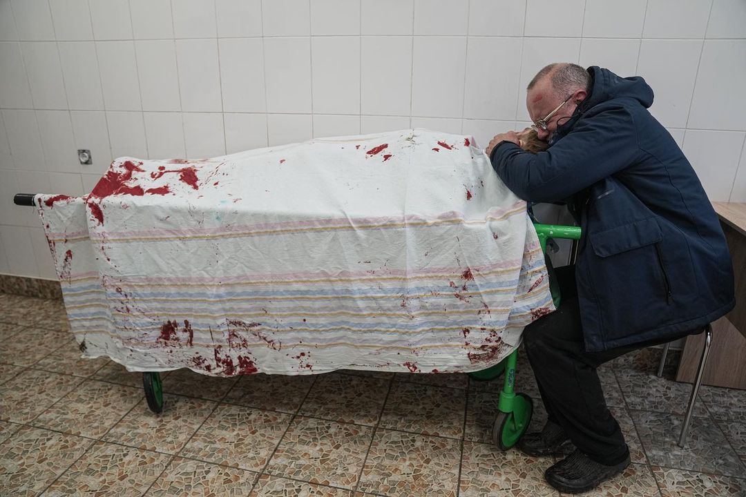 Сергій, батько підлітка Іллі, плаче над тілом сина, який лежить на ношах у лікарні Маріуполя, 2 березня 2022 року. Фото: Євген Малолєтка.