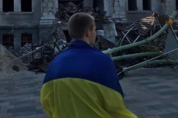 Un joven con la bandera de Ucrania sale a la plaza cerca del Teatro Dramático bombardeado en Mariúpol