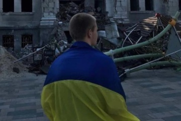 Marioupol : Un jeune homme avec un drapeau ukrainien s’est fait prendre en photo devant le théâtre détruit par une frappe russe 