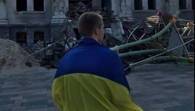 Un joven con la bandera de Ucrania sale a la plaza cerca del Teatro Dramático bombardeado en Mariúpol