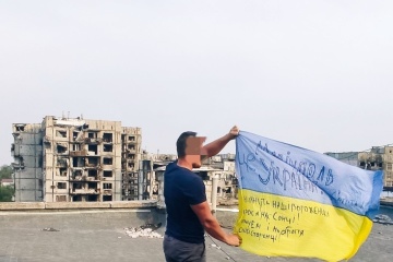 マリウポリの建物屋上で市民がウクライナ国旗を広げる