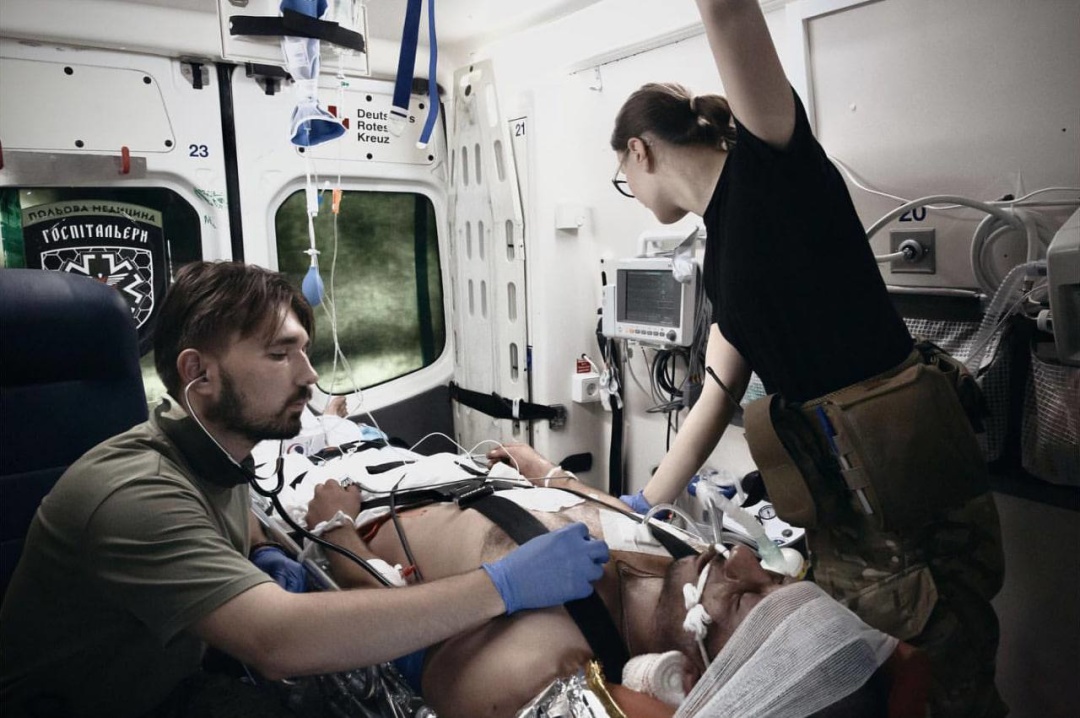 Ростислав Юзьків та Іванна Чобанюк надають допомогу пораненому українському бійцю дорогою у госпіталь / Фото: John Beck