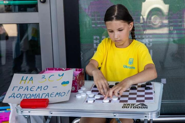 10-річна Валерія Єжова грає у шашки з перехожими. Юна волонтерка вже зібрала 21 тисячу гривень і передала зароблене у благодійний фонд Сергія Притули / Фото з фейсбук-сторінки мами дівчинки