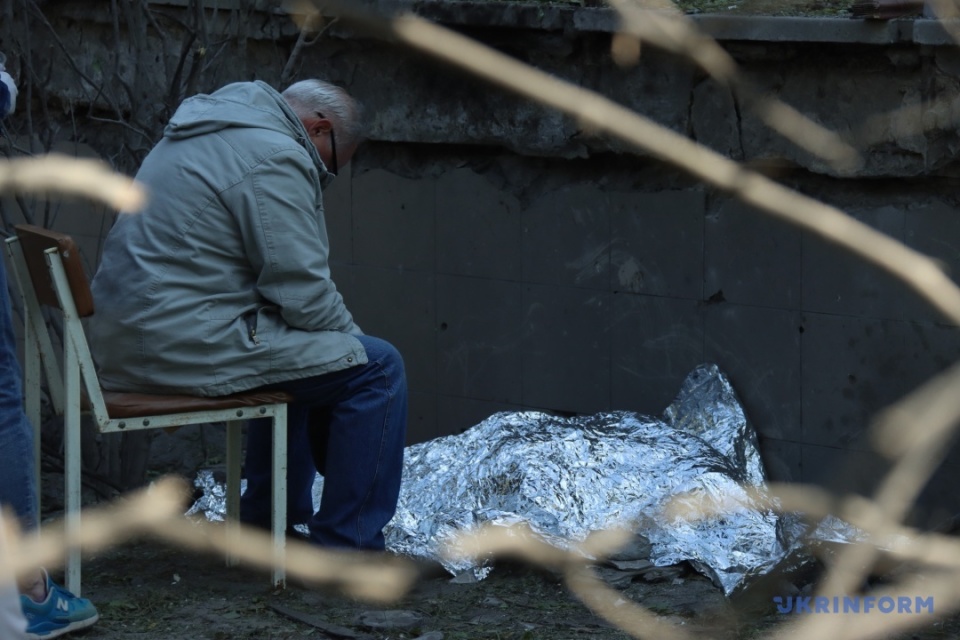 Дідусь біля загиблої онуки поруч з будівлею дитячої поліклініки / Фото: Анатолій Сірик. Укрінформ