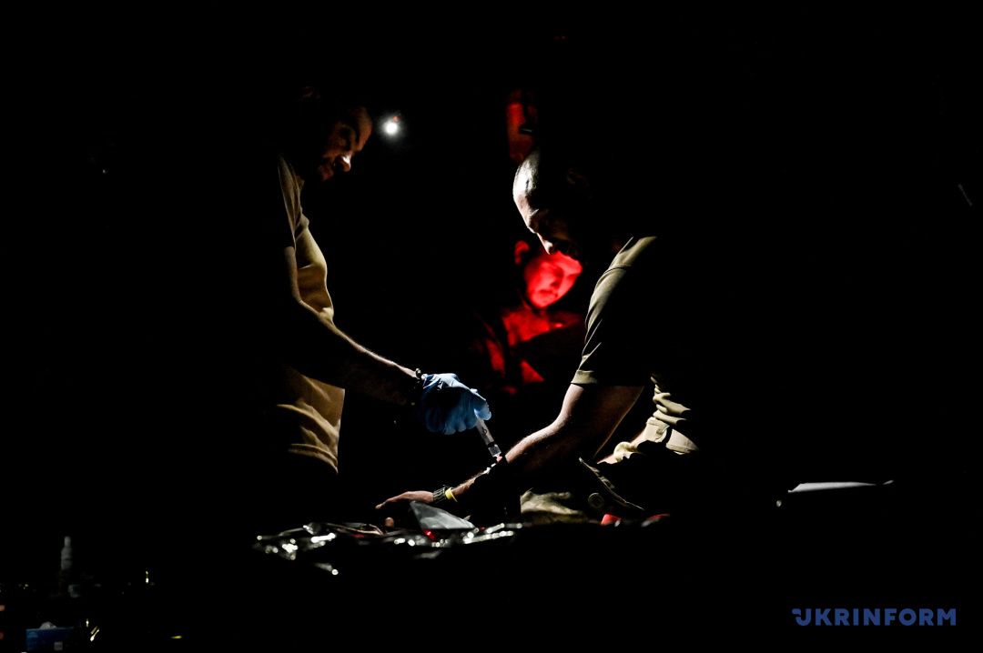 Медики надають першу медичну допомогу пораненому при світлі ліхтаря у стабілізаційному пункті медичної служби однієї з бригад, що воює на запорізькому напрямку, Запорізька область, 27 липня 2023 року. Фото: Дмитро Смольєнко