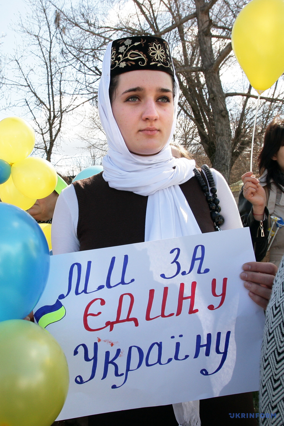クリミア・タタール人の装束で「私たちは単一ウクライナを支持」と書かれたプラカードを持つ女性　２０１４年３月５日、バフチサライ　写真：アルヴィダス・シェメタス