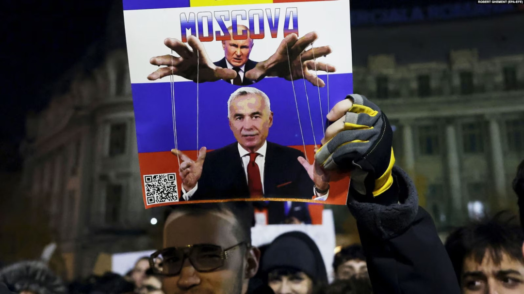 Плакат, на якому зображений керівник Росії Володимир Путін і Келін Джорджеску, який пройшов до другого туру на виборах президента Румунії, на акції протесту в румунській столиці. Бухарест, 25 листопада 2024 року. Згодом президентські вибори в Румунії були скасовані