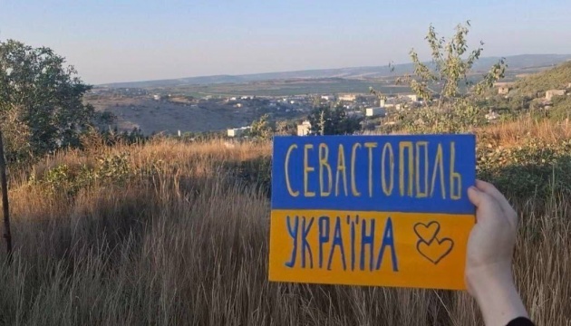 ロシア占領地でウクライナの活動家がウクライナ国旗を示す