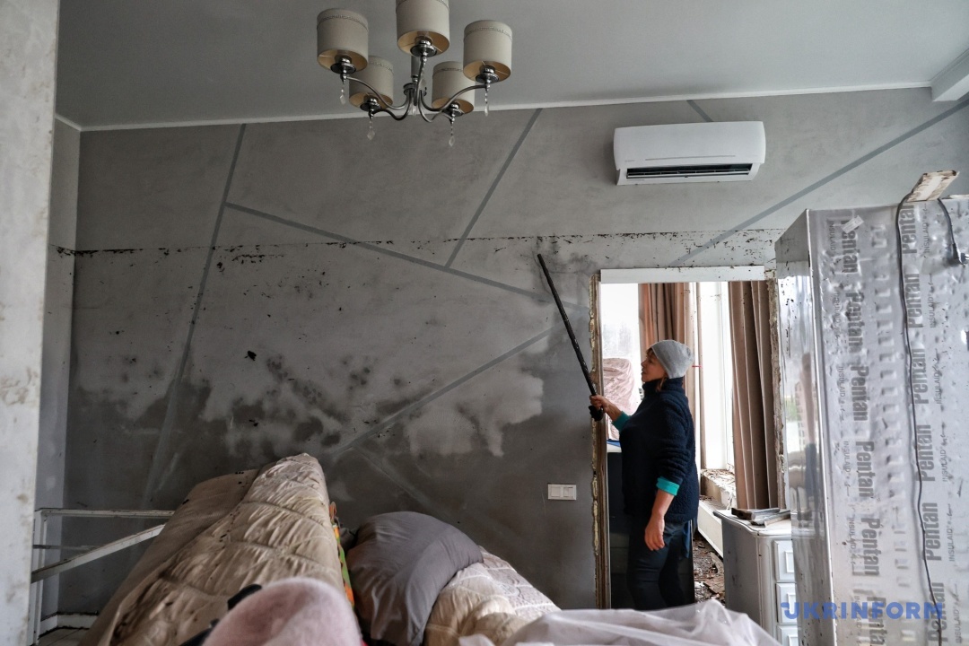 Лара показує рівень води в її будинку